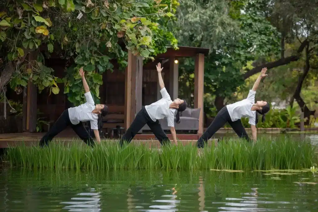 3 women doing yoga by a see